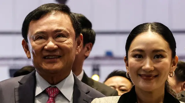 Thaksin and Paetongtarn smiling as they stand side by side.
