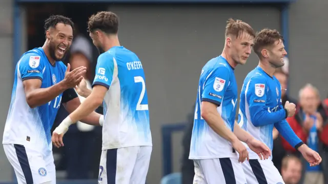 Kyle Wootton high fives with Corey O'Keeffe on the left as Owen Moxon and Ollie Norwood walk on the right