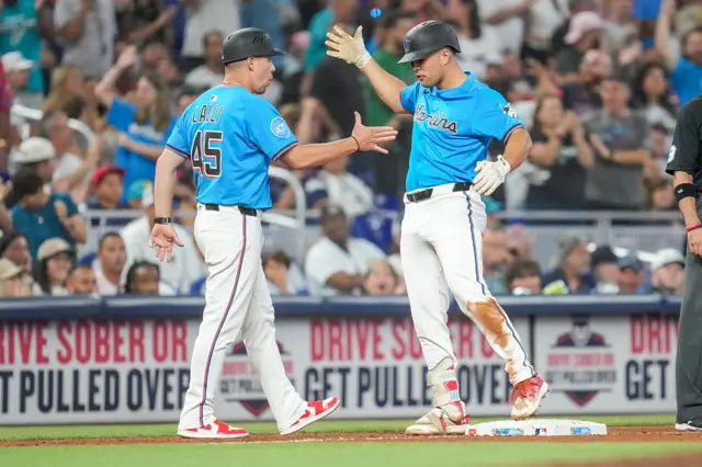 Jakob Marsee of the Miami Marlins celebrates with third base coach Blake Lalli after hitting a triple