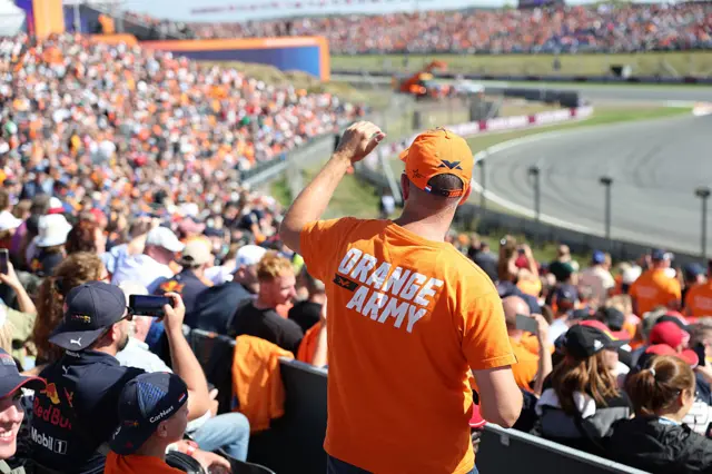 Rear view of a fan stood up in a Zandvoort grandstand with 'Orange Army' on the back of his orange t-shirt