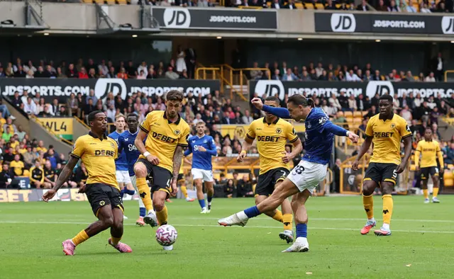 Jack Grealish of Everton shoots whilst under pressure from Jackson Tchatchoua and Santiago Bueno of Wolverhampton Wanderers during the Premier League match between Wolverhampton Wanderers and Everton at Molineux