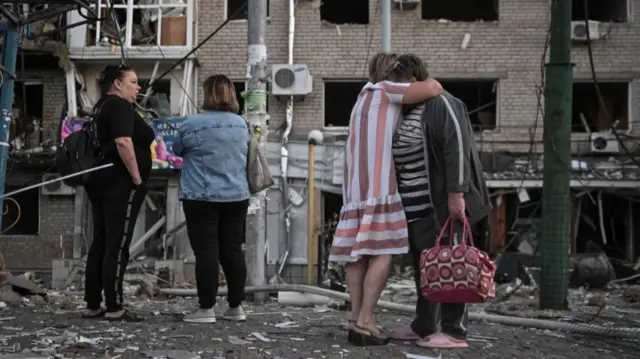 Residents stand at the site of an apartment building hit during a Russian drone and missile strike, amid Russia's attack on Ukraine, in Zaporizhzhia