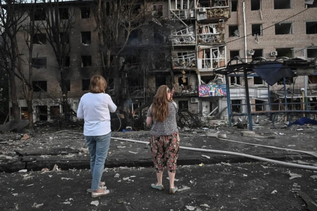 Residents stand at the site of an apartment building