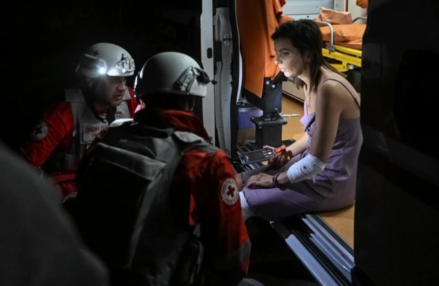 Medical workers treated a women who sits in an ambulance with a bandage around her left arm