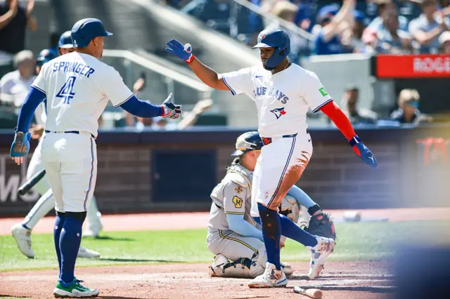 Vladimir Guerrero Jr. #27 and George Springer #4 of the Toronto Blue Jays celebrate at the plate as they score off a double from the bat of Nathan Lukes #38 in the first inning