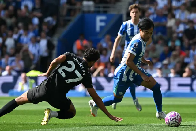 Kaoru Mitoma (R) runs past Manchester City's Portuguese midfielder #27 Matheus Nunes
