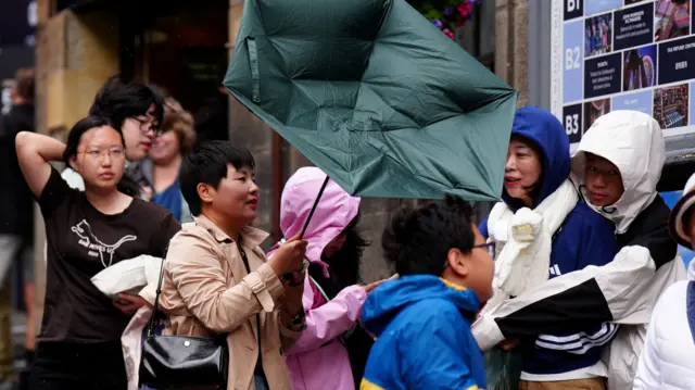 A woman holding a green umbrella which has been blown inside out during Storm Floris in Edinburgh
