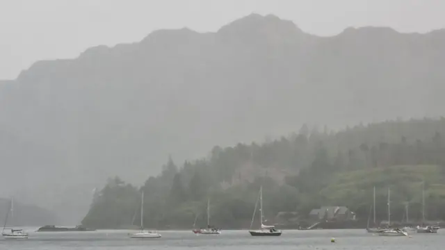 Ships moored in the sea surrounded by low, wet cloud