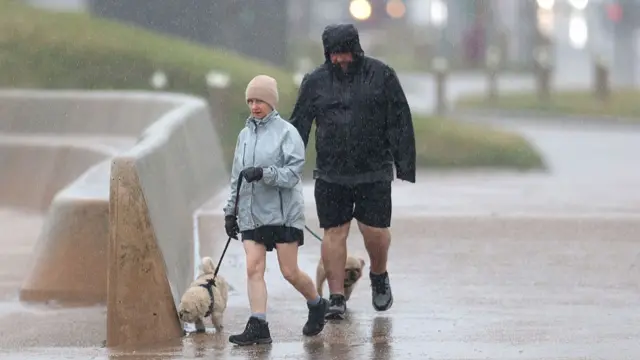 A couple braves the weather on Blackpool Promenade in Blackpool
