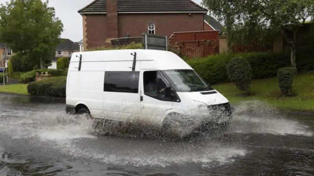 A vehicle drives through localised flooding in the East End of Glasgow, Scotland, Britain