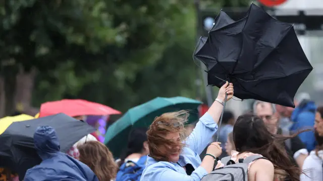 A woman struggles to hold an umbrella
