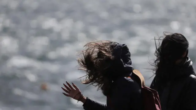Women walk on the esplanade, as Storm Floris hits Scotland