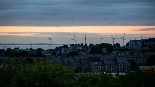 Offshore wind turbines beyond residential houses along the coast in Aberdeen