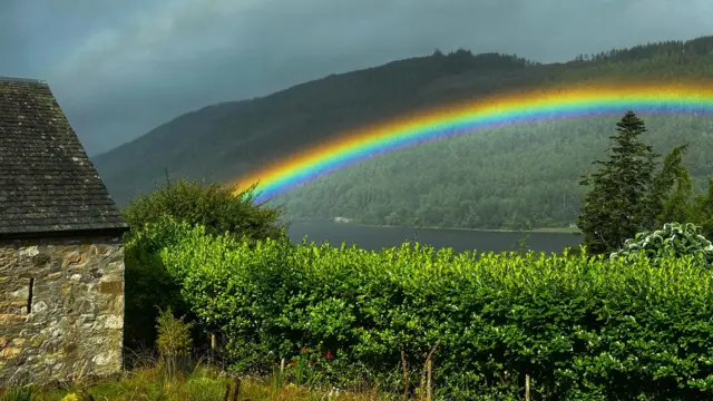 A rainbow in Scotland next to a barn building