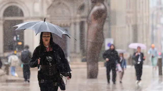 People use umbrellas as it rains in Victoria Square, Birmingham.