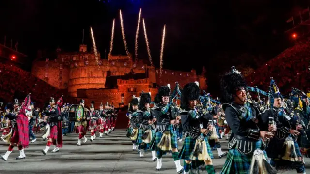 Edinburgh Military tattoo with people in kilts playing bagpipes.
