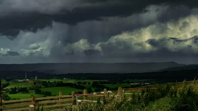 Fields with dark cloudy skies above.