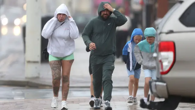 A family fights against the wind as they walk down Blackpool Promenade