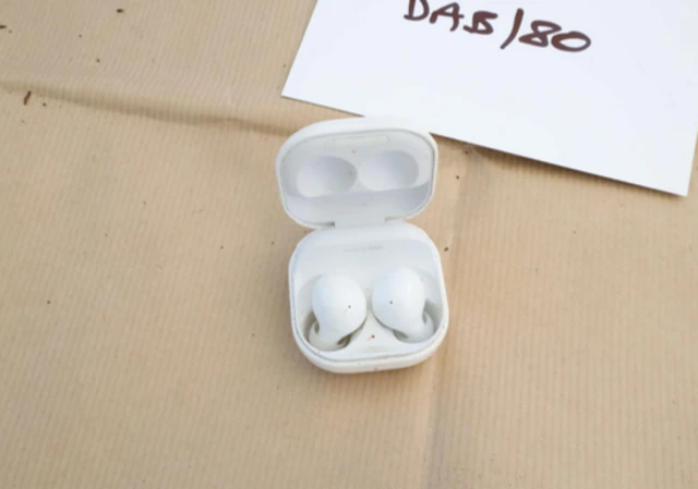 A pair of white wireless headphones in a plastic case, on brown paper.
