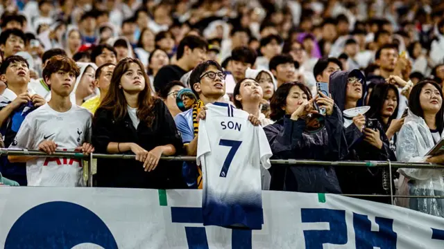 A spectator holds a shirt cheering Tottenham Hotspur's captain Son Heung-min