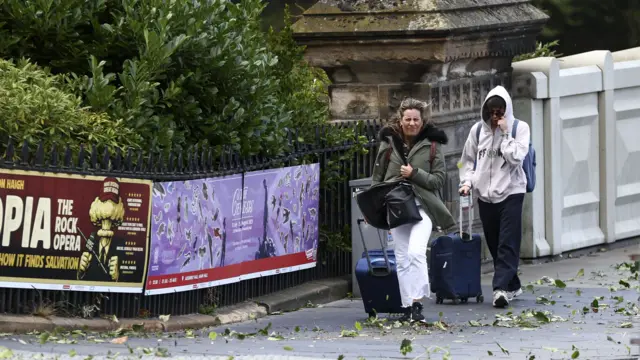 People walk on the Royal Mile with strong winds as Storm Floris triggers weather warnings across Scotland