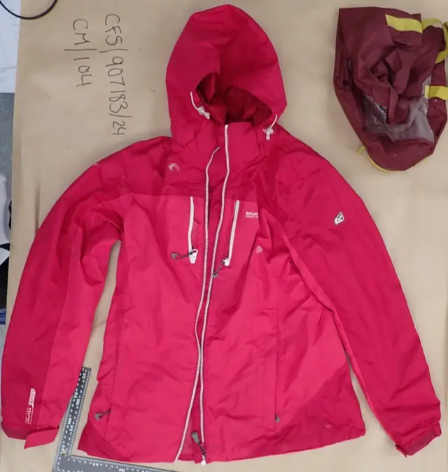A bright pink waterproof regatta jacket is laid out on brown paper next to a reference number