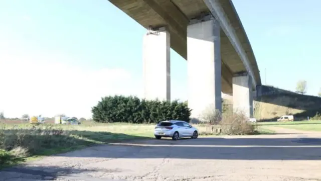 A view underneath the Orwell Bridge. Police cars and vans are parked around the area.