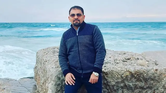 A Gazan man leans on a rock by the beach in Gaza.