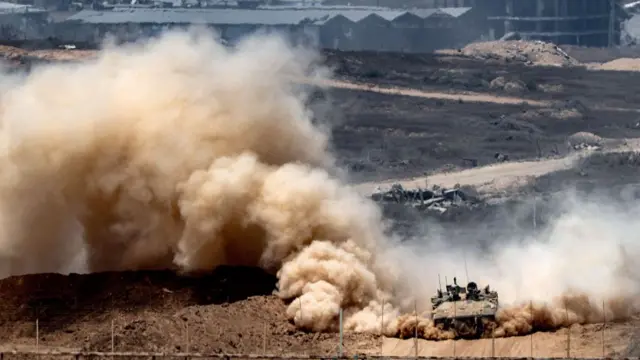 An Israeli army infantry-fighting vehicle leaves a cloud of dust as it moves at a position along Israel's southern border with the Gaza Strip