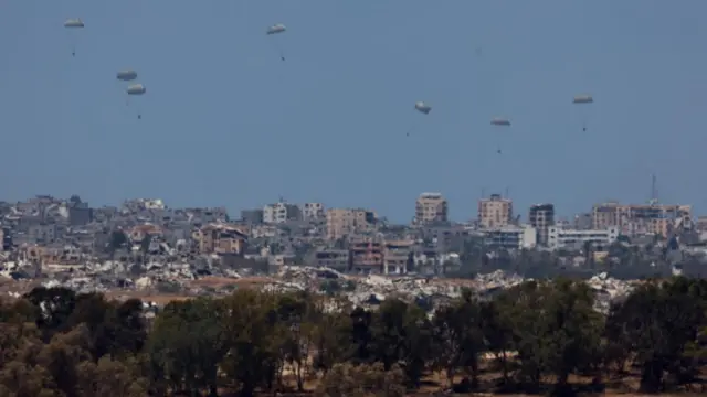 An aircraft drops humanitarian aid packages over Gaza, as seen from Israel