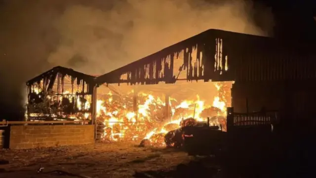 A picture taken by the farmers shows the remains of a barn and a large fire burning. All that is left is the barn's steel structure.
