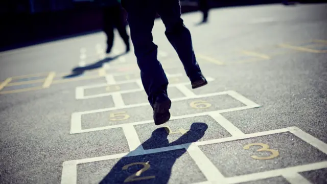 A child is seen playing hopscotch in a playground