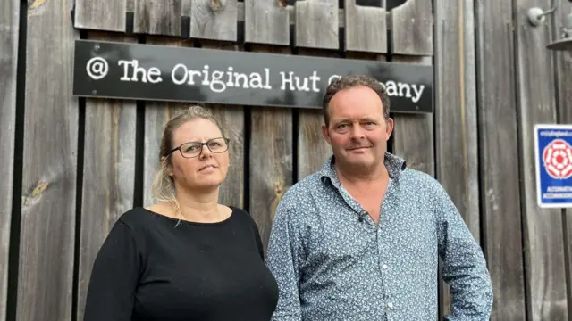 A man and woman stand in front of a cafe.