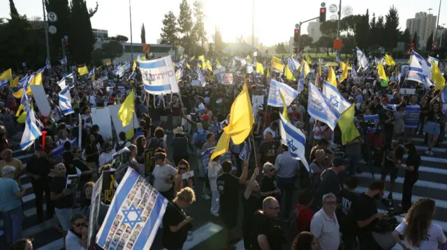 A large group holds Israeli flags carrying the photos of hostages kidnapped during the 7 October 2023 Hamas attack as well as yellow flags as they march in Jerusalem