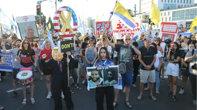 Crowds of Israelis carrying flags and placards with pictures of the hostages as they protest in downtown Jerusalem