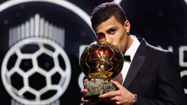 Manchester City's Spanish midfielder Rodri kisses the trophy as he receives the Ballon d'Or award