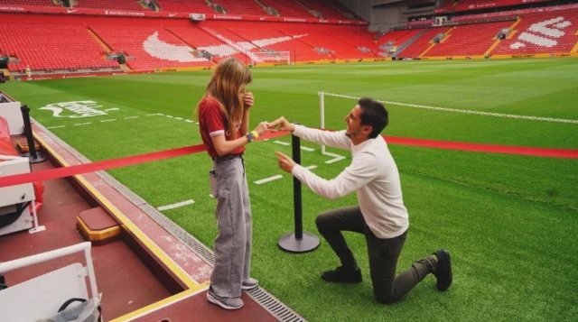 A man is on one knee proposing to a woman in Liverpool shirt at Anfield
