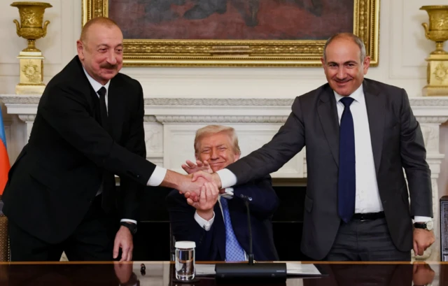 U.S. President Donald Trump holds the hands of Azerbaijan's President Ilham Aliyev and Armenia's Prime Minister Nikol Pashinyan as they shake hands between each other during a trilateral signing event, at the White House
