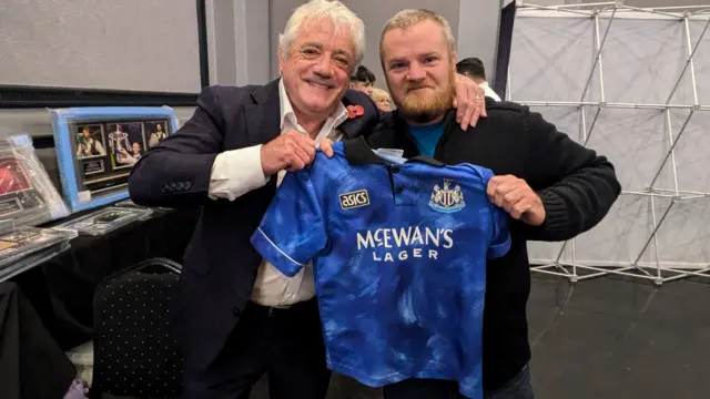 A picture of Kevin Keegan with holding a Newcastle shirt with a supporter