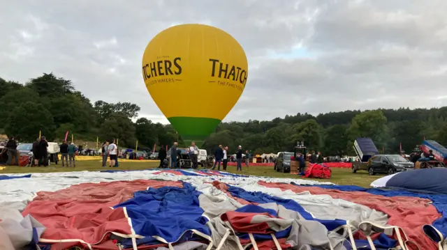 A yellow balloon with an inflated canopy gets ready