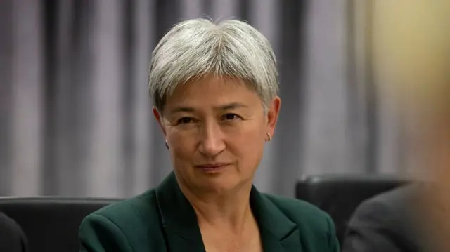 Australian Minister for Foreign Affairs Penny Wong is pictured with short grey hair and wearing a green suit.