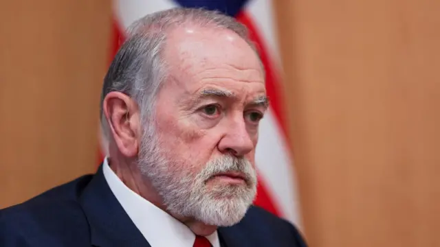 Mike Huckabee looks ahead wearing a suit.