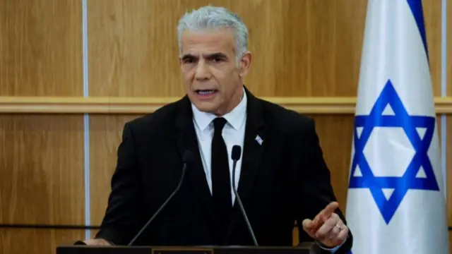 Yair Lapid pictured speaking at a podium in front of an Israeli flag