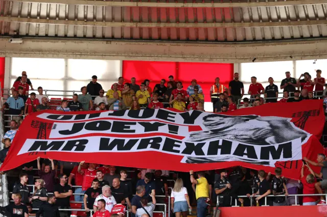 Wrexham fans hold up a large banner in memory of former Wrexham player Joey Jones