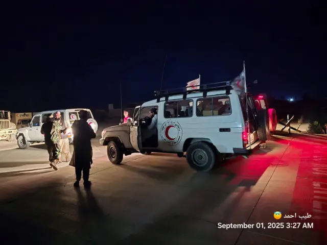 Men stand in fronf of three ambulances at an airport in Afghanistan