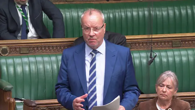 Man addressing commons in suit and tie