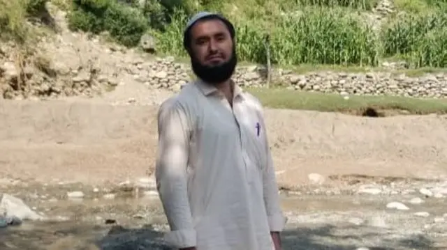 A man stands in a river in a mountainous area of Afghanistan.