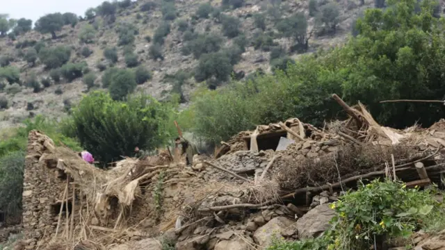 Men work through rubble on a mountain
