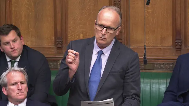 Neil Hudson in suit and tie addressing commons
