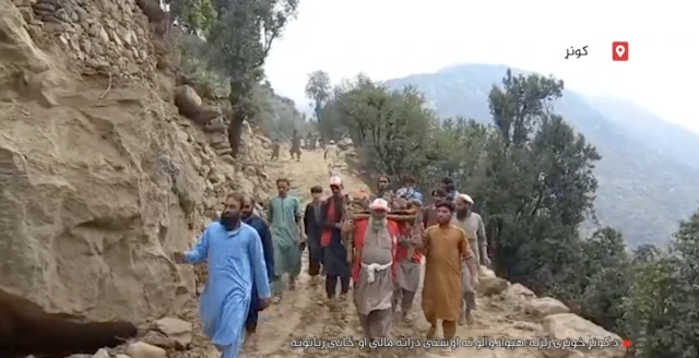 Picture showing a group of rescuers carrying a person on a stretcher in a mountainous area.